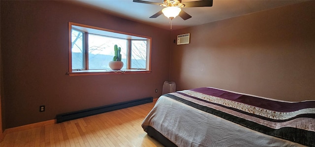 bedroom featuring ceiling fan, a baseboard heating unit, a wall unit AC, and light hardwood / wood-style floors