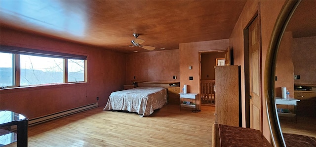 bedroom with ceiling fan, light wood-type flooring, and a baseboard heating unit