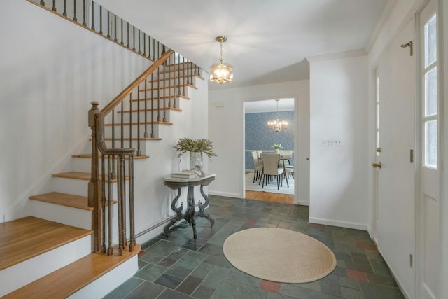 entryway with ornamental molding and an inviting chandelier