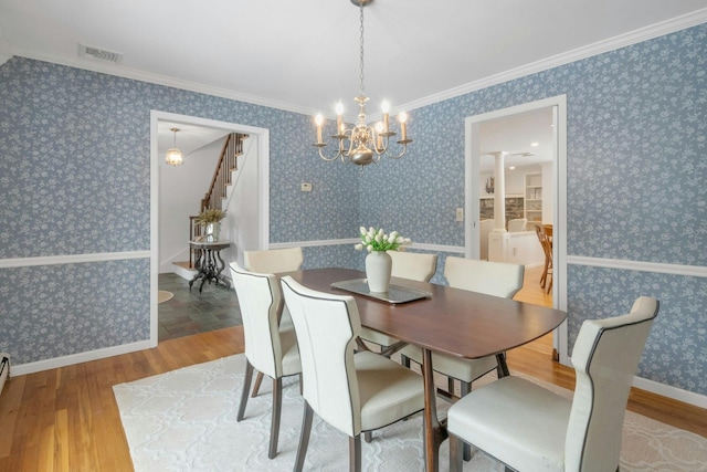 dining space with an inviting chandelier, hardwood / wood-style flooring, and ornamental molding