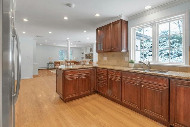 kitchen with light stone countertops, sink, stainless steel refrigerator, and kitchen peninsula