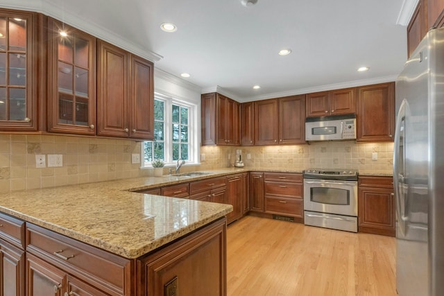 kitchen featuring appliances with stainless steel finishes, sink, light stone counters, crown molding, and light hardwood / wood-style flooring