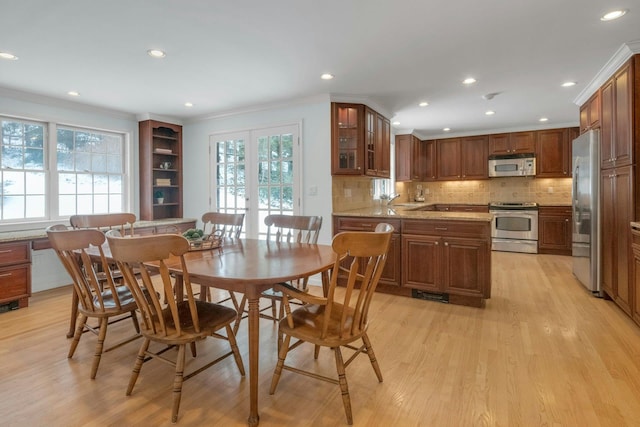 dining space featuring ornamental molding, light hardwood / wood-style floors, and french doors