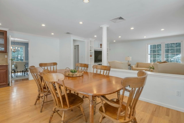 dining area with ornamental molding, light hardwood / wood-style floors, a healthy amount of sunlight, and ornate columns