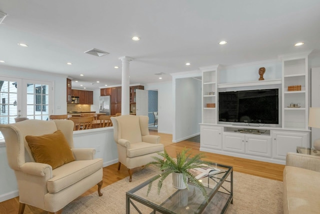 living room with crown molding, light hardwood / wood-style flooring, decorative columns, and french doors