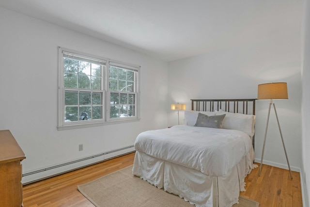 bedroom featuring baseboard heating and light hardwood / wood-style flooring