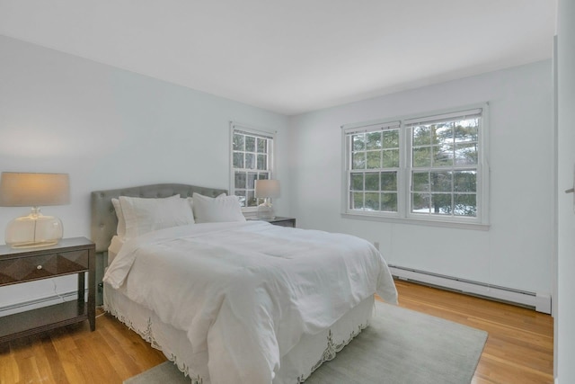 bedroom with light hardwood / wood-style flooring and baseboard heating