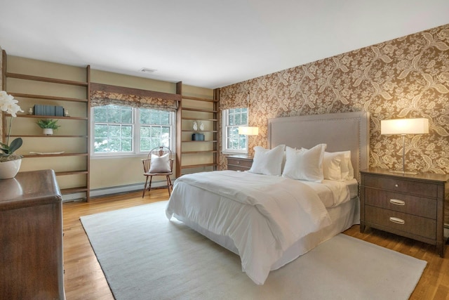 bedroom with a baseboard radiator and light hardwood / wood-style flooring