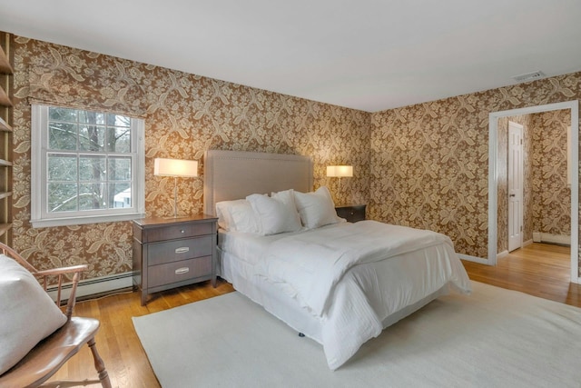 bedroom with a baseboard radiator and light wood-type flooring