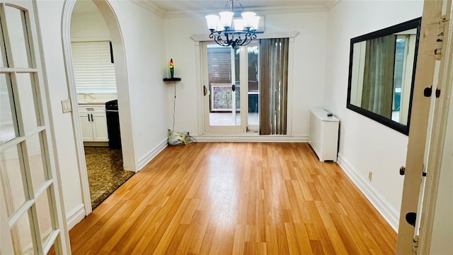 unfurnished dining area featuring crown molding, plenty of natural light, a chandelier, and light wood-type flooring