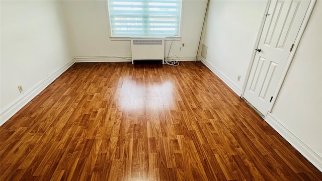 unfurnished bedroom featuring hardwood / wood-style flooring and radiator heating unit