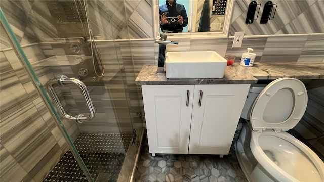 bathroom featuring toilet, a shower with shower door, tasteful backsplash, tile walls, and vanity