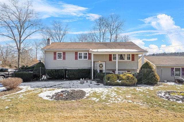 split foyer home featuring a chimney and fence