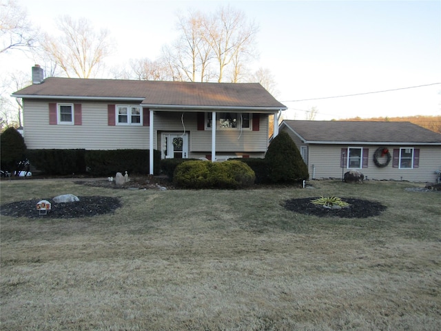 bi-level home featuring a front yard and a chimney