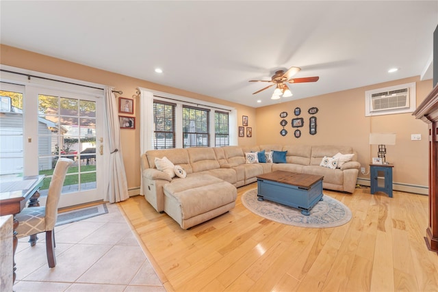 living room featuring baseboard heating, ceiling fan, a wall mounted AC, and light hardwood / wood-style floors