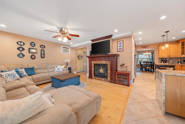 living room featuring ceiling fan, a wall unit AC, light hardwood / wood-style floors, and baseboard heating