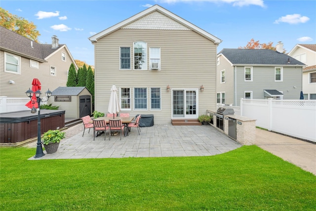 rear view of house featuring a shed, a yard, a patio area, and a hot tub