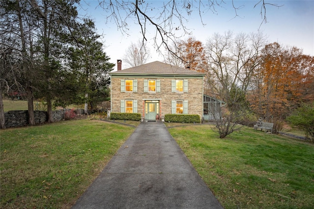 view of front facade with glass enclosure and a front yard