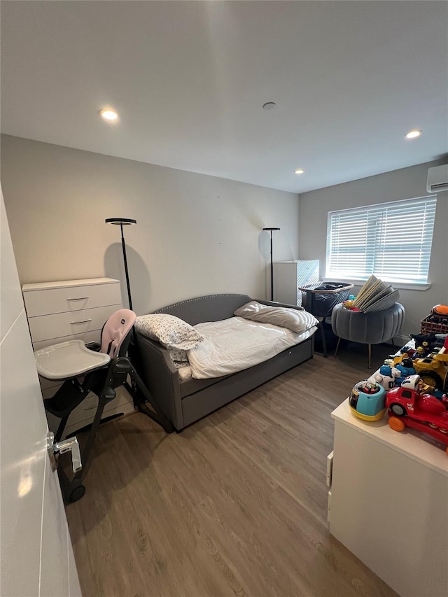 bedroom featuring wood-type flooring and a wall mounted AC