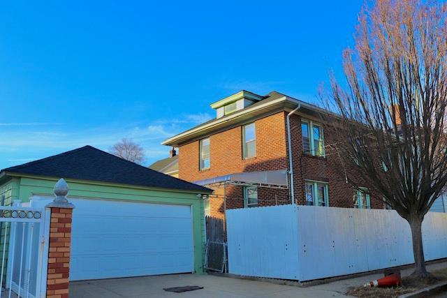 view of property exterior featuring fence, brick siding, and driveway