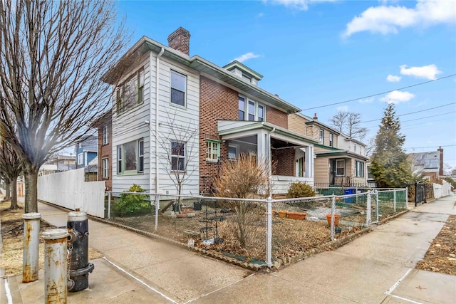 view of side of home featuring a fenced front yard and a chimney