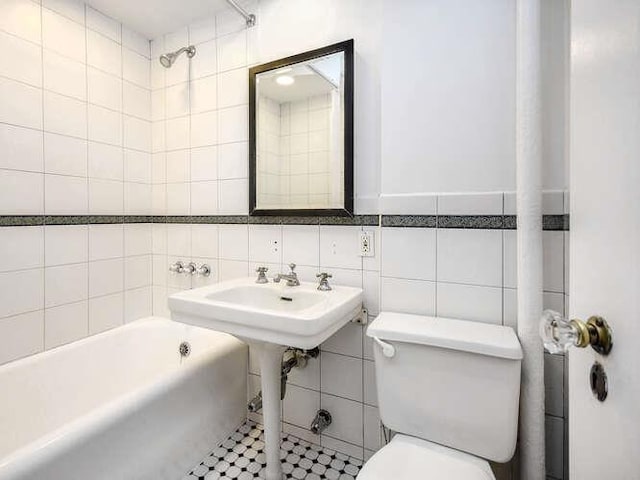 bathroom featuring tile walls, toilet, and shower / bath combination