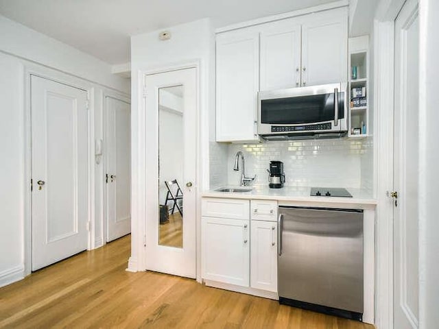 bar featuring appliances with stainless steel finishes, light hardwood / wood-style floors, sink, and white cabinets