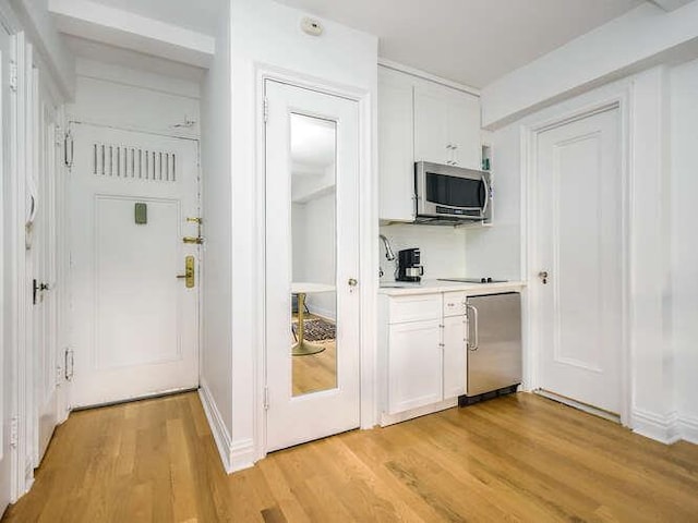 kitchen featuring white cabinetry, light hardwood / wood-style floors, and appliances with stainless steel finishes