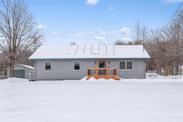 snow covered house with an outdoor structure and a garage