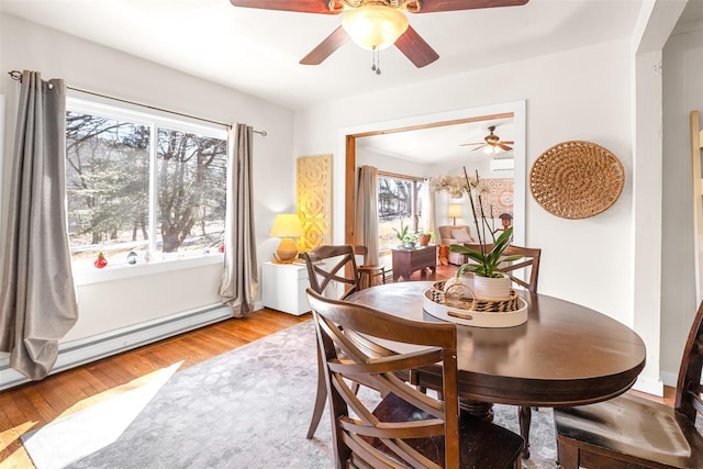 dining area featuring a baseboard heating unit, ceiling fan, and light wood-style flooring