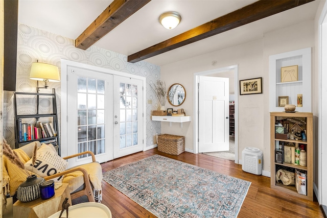 living area with french doors, beamed ceiling, wood finished floors, and wallpapered walls