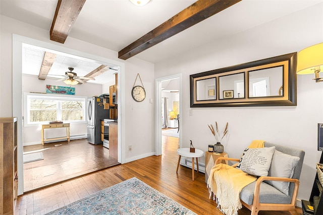 sitting room featuring ceiling fan, beam ceiling, hardwood / wood-style flooring, and baseboards