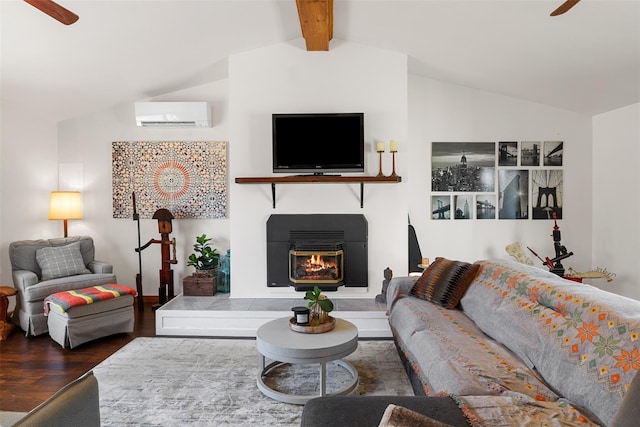 living area with a glass covered fireplace, a wall unit AC, lofted ceiling with beams, ceiling fan, and wood finished floors