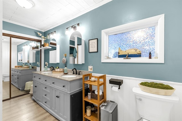 bathroom featuring toilet, a wainscoted wall, ornamental molding, wood finished floors, and vanity