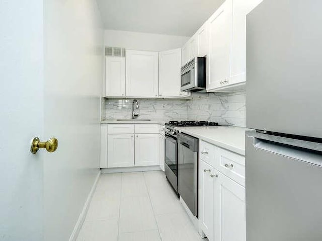 kitchen featuring white cabinetry, appliances with stainless steel finishes, sink, and decorative backsplash