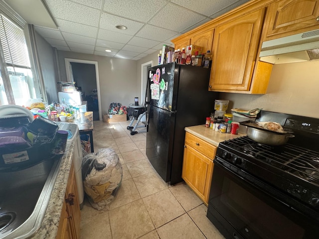 kitchen with light tile patterned floors, under cabinet range hood, light countertops, a paneled ceiling, and black appliances