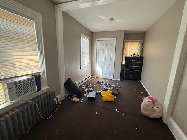 bedroom with radiator, cooling unit, baseboards, and a closet