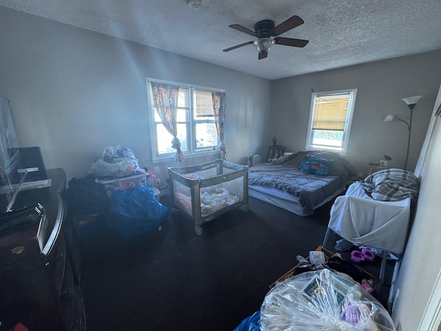 bedroom with a ceiling fan, multiple windows, and a textured ceiling