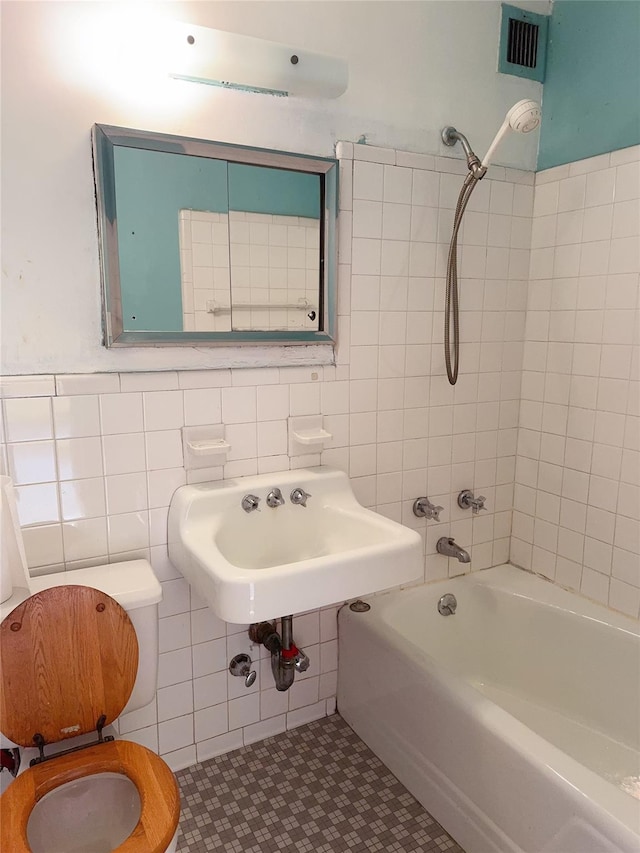 full bath featuring visible vents, bathing tub / shower combination, tile patterned floors, a sink, and tile walls