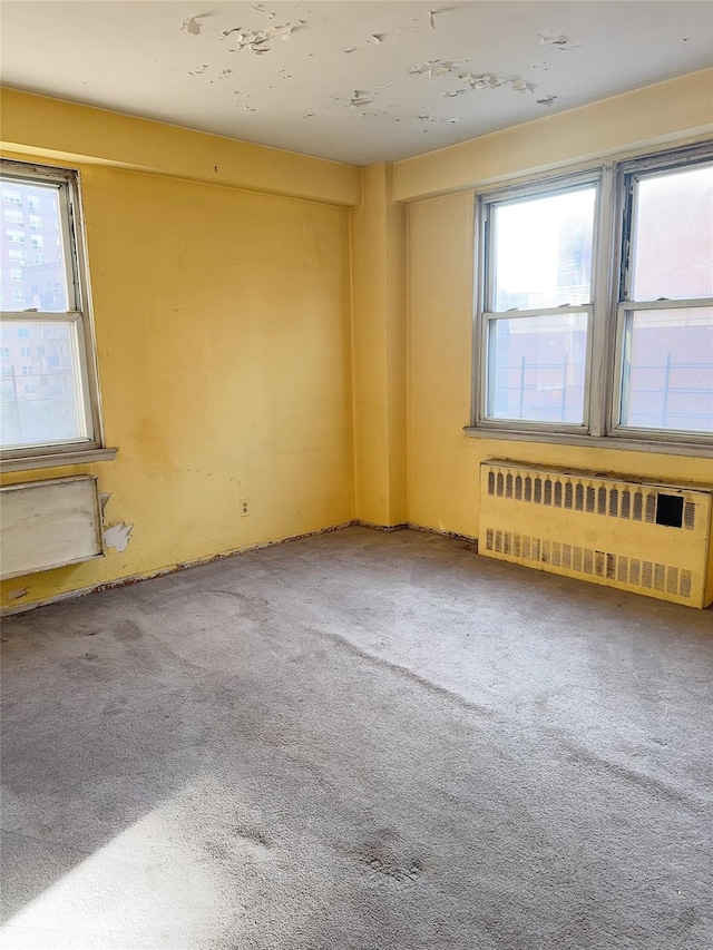 spare room with carpet floors and radiator heating unit