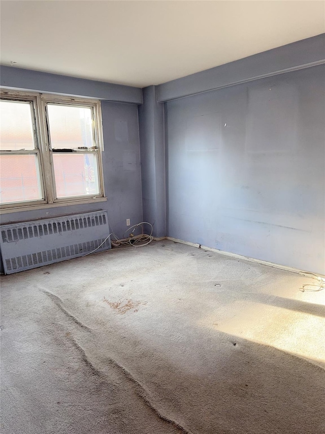 carpeted spare room featuring radiator