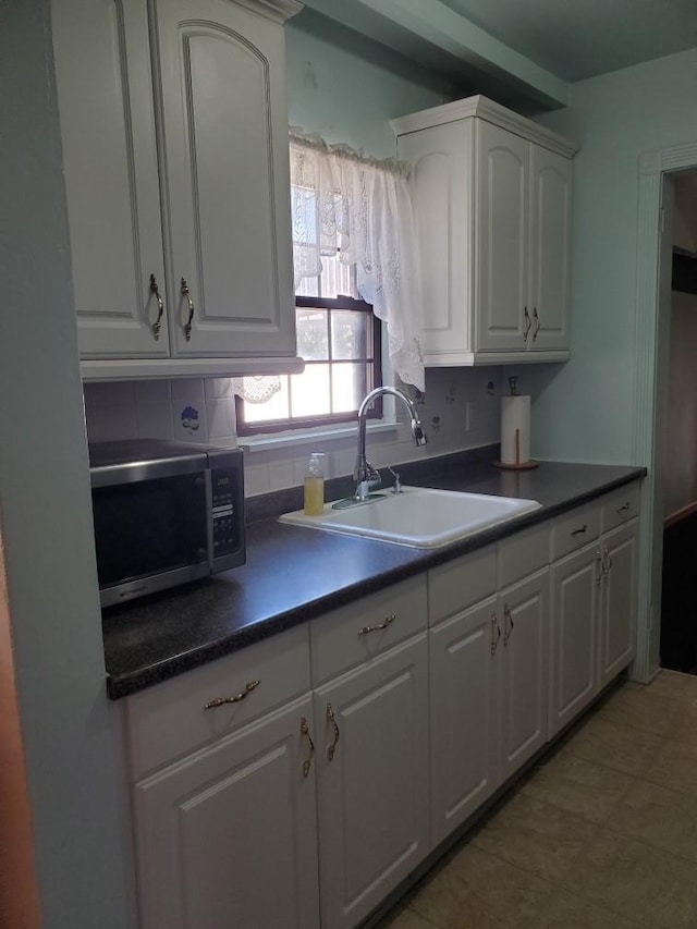 kitchen with tasteful backsplash, sink, and white cabinets