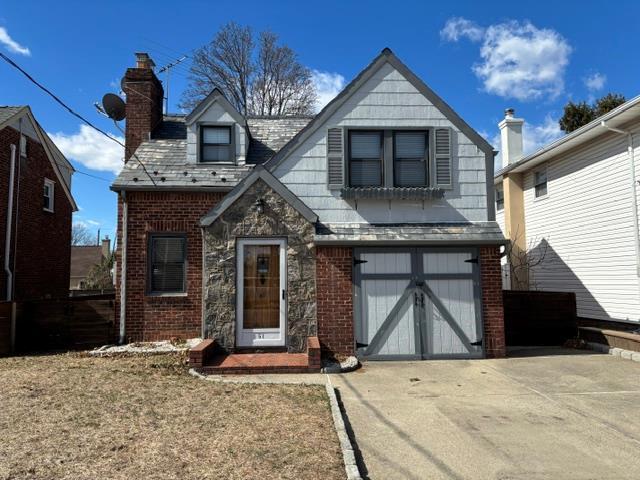 view of front of property featuring driveway, a garage, and brick siding