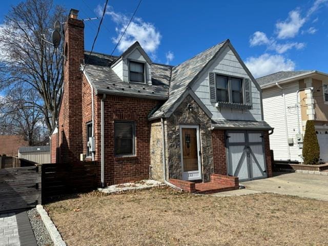 view of front of house with brick siding, driveway, a chimney, and an attached garage