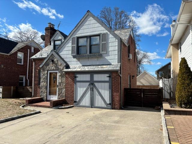 view of front of home with a garage, brick siding, driveway, and a chimney