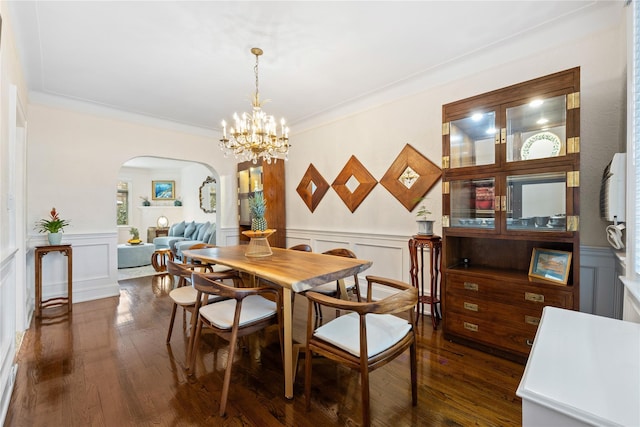 dining area featuring ornamental molding, dark wood-type flooring, and an inviting chandelier