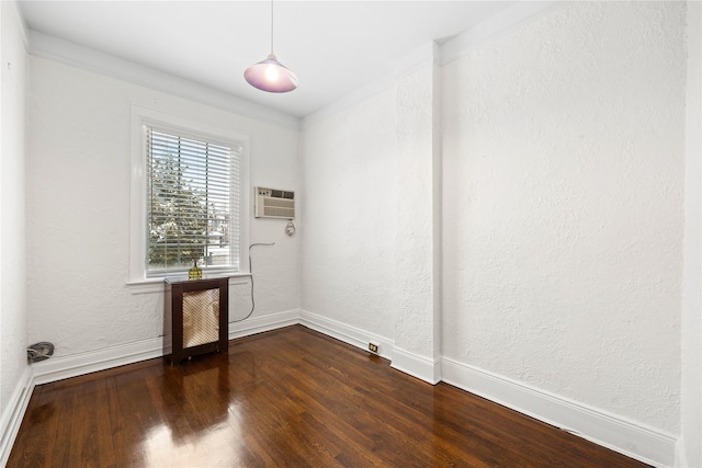 empty room featuring crown molding, an AC wall unit, and dark wood-type flooring