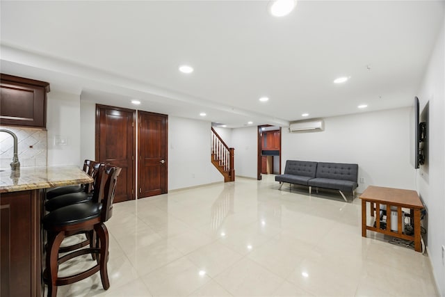 interior space with a breakfast bar, a wall mounted AC, light stone countertops, and backsplash