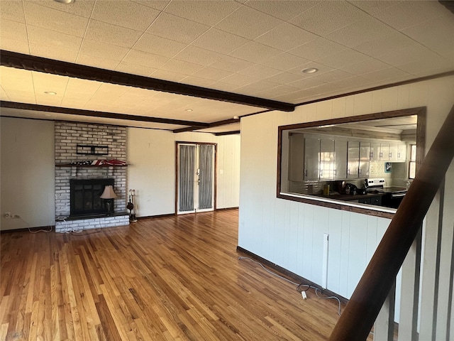 unfurnished living room with beam ceiling, a fireplace, and light hardwood / wood-style flooring