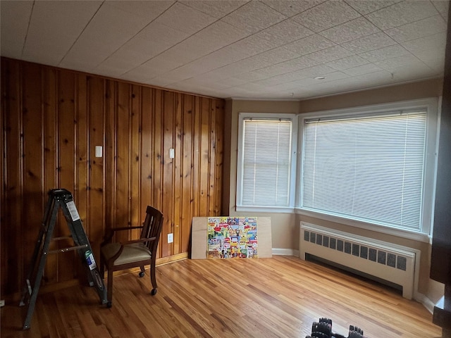 sitting room with radiator heating unit, wood-type flooring, and wood walls